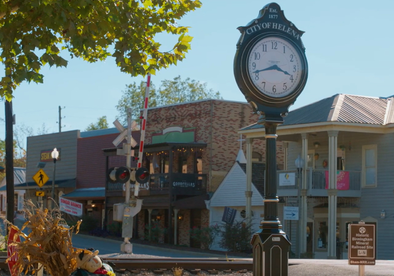 man on camping trip sitting in front of fire with cell phone on hand