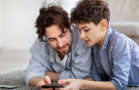 father and son looking into smartphone device