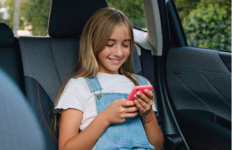 Girl sitting in car texting on phone.